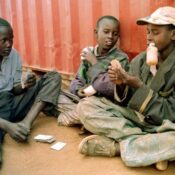 picture of street children seated one sniffing glue while they play a gam